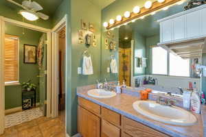 Full bath featuring a shower stall, double vanity, a bath, and ceiling fan