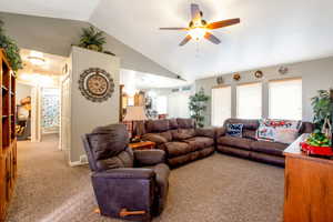 Carpeted living room with vaulted ceiling and a ceiling fan