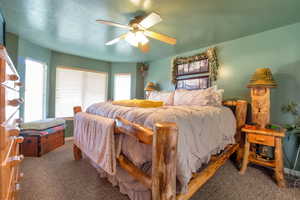 Bedroom featuring a textured ceiling, dark carpet, and a ceiling fan