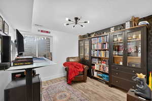 Living area featuring a textured ceiling, a chandelier, and light wood-style floors