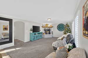 Living room with ornamental molding, arched walkways, and carpet flooring