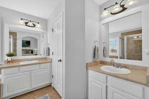 Bathroom with a shower stall, ensuite bath, two vanities, and light tile patterned flooring