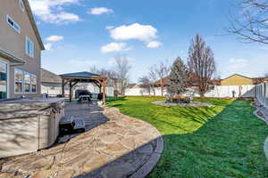 Fenced backyard with a patio, a gazebo, an outdoor fire pit, and a hot tub