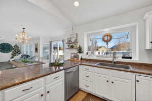 Kitchen with white cabinetry, stainless steel dishwasher, a chandelier, a peninsula, and light tile patterned floors