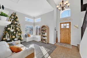 Tiled foyer with a towering ceiling, stairs, a chandelier, and ornamental molding