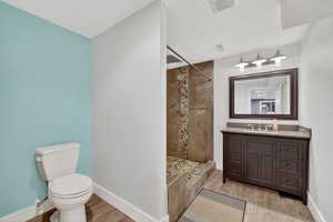 Full bathroom with vanity, light wood-style flooring, and a tile shower