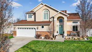 Traditional-style home with stone siding, roof with shingles, concrete driveway, and stucco siding