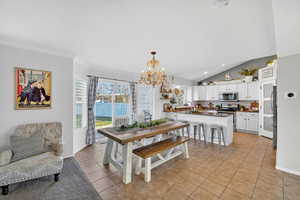 Dining space featuring a chandelier, light tile patterned floors, lofted ceiling, and recessed lighting
