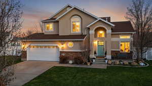 Traditional home featuring driveway, stone siding, and stucco siding