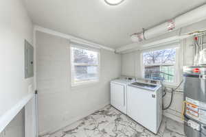 Laundry room featuring water heater, light marble finish flooring, electric panel, independent washer and dryer, and concrete block wall