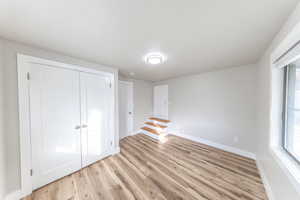 Unfurnished bedroom featuring light wood-style floors and a closet