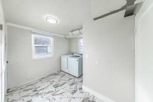 Laundry area with washing machine and clothes dryer, light marble finish flooring, and a textured ceiling