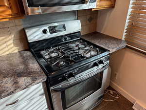 Kitchen with dark countertops, stainless steel appliances, and tasteful backsplash