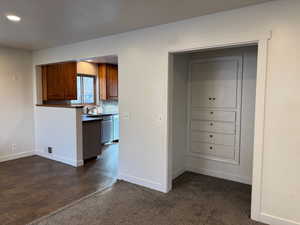 Kitchen featuring dark countertops, brown cabinets, dark colored carpet, decorative backsplash, and recessed lighting