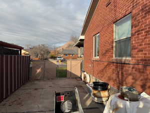 View of side of home with a gate, brick siding, and a patio