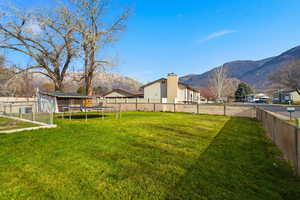 Fenced backyard featuring a trampoline and a mountain view