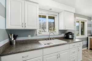 Kitchen with white cabinetry, dark countertops, and plenty of natural light