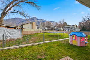 Fenced backyard with a trampoline, a mountain view, a residential view, and a playground