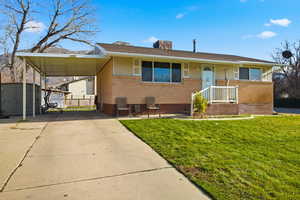 View of front facade with a shed, driveway, a carport, and brick siding