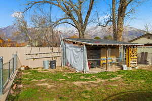 Fenced backyard with a mountain view, an outdoor structure, and exterior structure