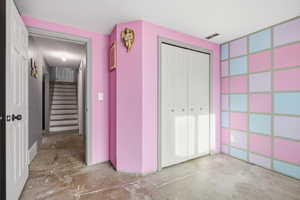 Corridor featuring unfinished concrete floors, stairs, and a textured ceiling
