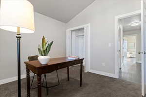 Office area with vaulted ceiling and dark carpet