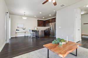 Living area with a ceiling fan, recessed lighting, and dark wood-type flooring