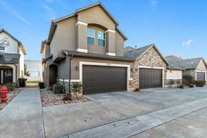 Traditional home featuring stucco siding, concrete driveway, and stone siding