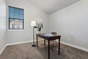 Carpeted home office featuring lofted ceiling and baseboards