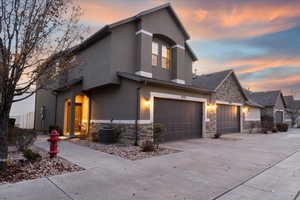View of front of house featuring stone siding, concrete driveway, and stucco siding