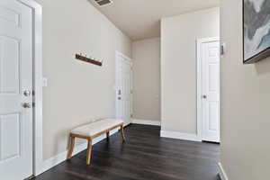 Hallway with dark wood-type flooring and baseboards