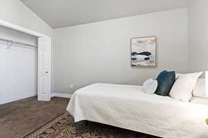 Bedroom with dark carpet, lofted ceiling, and a closet