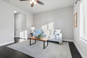 Living area with dark wood-type flooring and ceiling fan