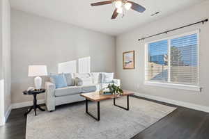 Living room with dark wood-style flooring and a ceiling fan