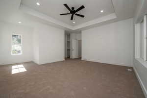 Unfurnished bedroom featuring a tray ceiling, carpet, recessed lighting, and ceiling fan