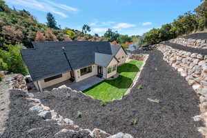 View of front facade with a patio, stucco siding, a front yard, and roof with shingles
