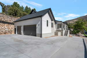 View of side of property featuring concrete driveway, board and batten siding, a shingled roof, a mountain view, and a garage