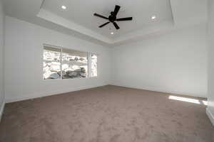 Carpeted empty room featuring a tray ceiling, ceiling fan, and recessed lighting