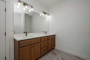 Full bath featuring light marble finish floors and double vanity