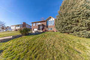Rear view of property with brick siding and a yard