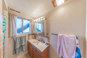 Full bath featuring a textured ceiling, a shower with curtain, vanity, and light tile patterned flooring