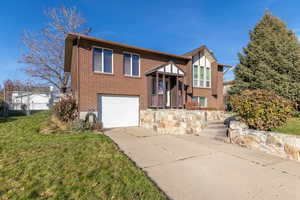 View of front of property featuring brick siding, a garage, and driveway