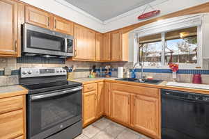 Kitchen featuring appliances with stainless steel finishes, crown molding, a textured ceiling, tasteful backsplash, and light tile patterned flooring