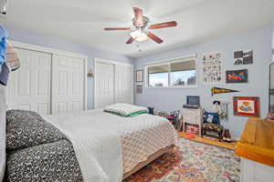Bedroom featuring two closets, wood finished floors, ceiling fan, and a textured ceiling