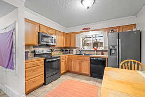 Kitchen with appliances with stainless steel finishes, a textured ceiling, light tile patterned flooring, decorative backsplash, and light countertops