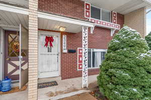 Property entrance featuring brick siding and covered porch