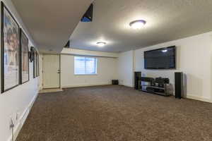 Unfurnished living room featuring a textured ceiling and dark colored carpet