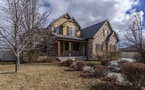 View of front of property with stone siding, a porch, and stucco siding
