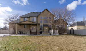 Rear view of house featuring a patio area, stucco siding, a hot tub, stone siding, and a gate