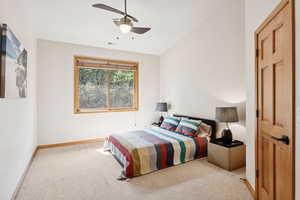 Carpeted bedroom with ceiling fan and baseboards